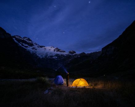 Tent lit up at night under a starry sky
