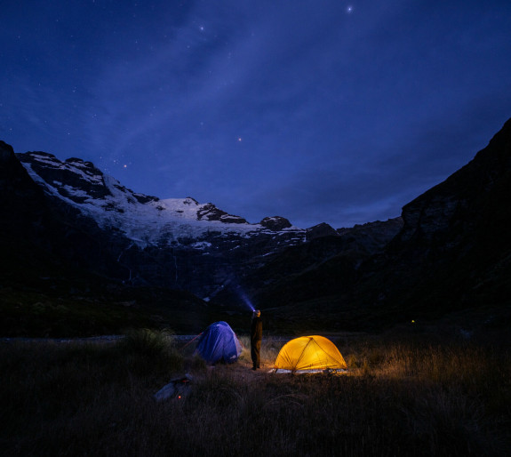 Tent lit up at night under a starry sky