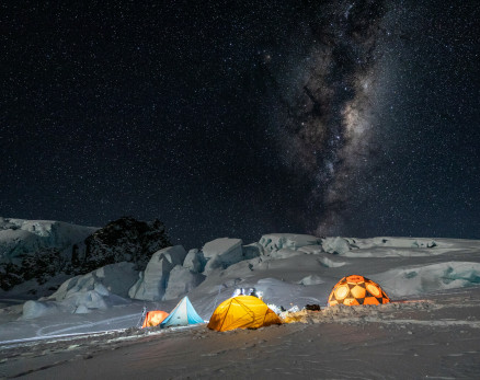 Tents lit up at night under a starry sky